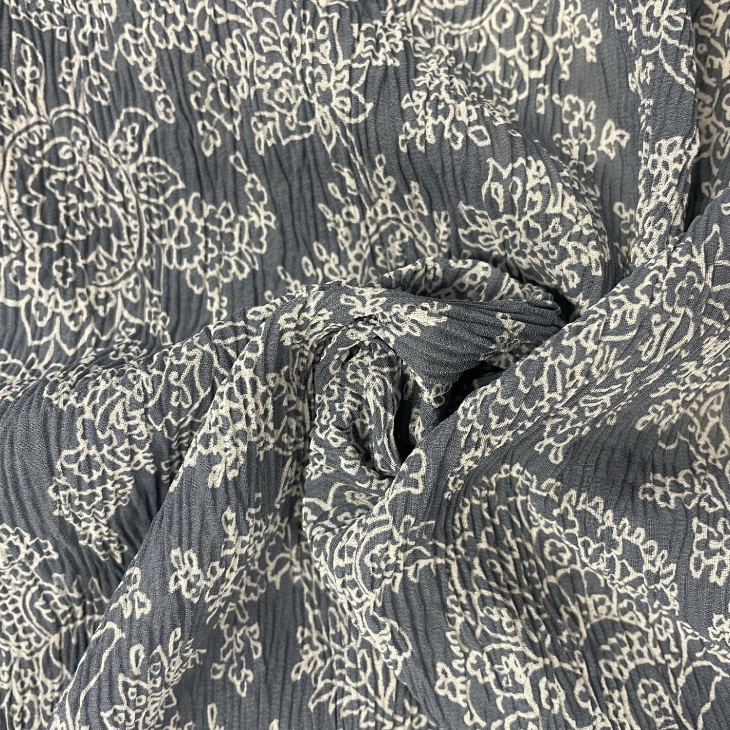 Lätt krinklad polyester tyg i blågrå med vitt mönster
