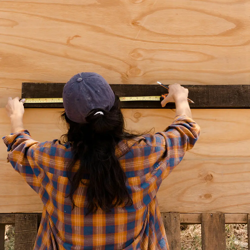 En tjej som mäter en planka mot en vägg