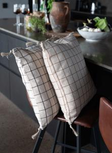 Kuddfodral Axel med tofsar, återvunnet material, vävda rutor i svart och beige.