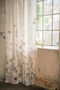 Gardin FLORA med ett klättrande blommönster från gardinens nederkant och uppåt i mjuka jordnära kulörer