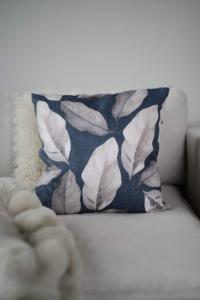 Kuddfodral PONZA med blad i grått och beige på blå bottenfärg