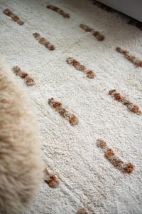 Matta TINE, tuftad i offwhite med bruna inslag, flätad frans i kortsidorna