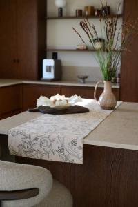 Bordslöpare ELLIE med ett snirklande fantasifullt bladmönster i grönt på beige botten