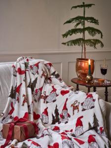 Pläd NOEL med tomtar, granar, hjärtan och halmjulbockar på ljust linnefärgad botten