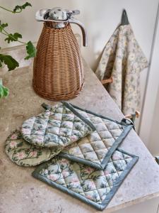 Grytlapp FANNY med beige blommor och gröna blad på grön bottenfärg