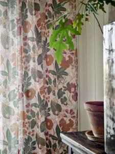 Gardin LAURA med blommor och blad i vinrött, grönt, rost och ockragult på linnefärgad botten